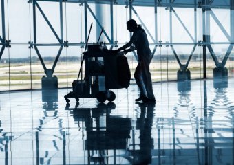 Reinigungskraft mit einem Wagen voller Equipment